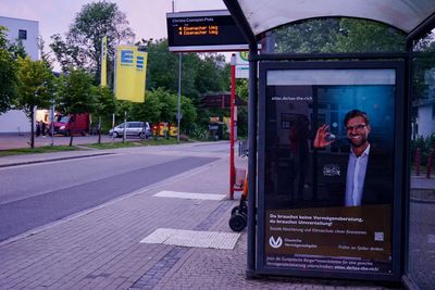 Blick auf eine Bushaltestelle, bei der das Werbeplakat gegen ein Fake-Plakat ausgetauscht wurde. Auf ihm ist Jürgen Klopp bei einer umgestalteten Werbung der Deutschen Vermögensberatung AG zu sehen und der für die Europäische Bürger*inneninitative "Tax the richt wirbt"