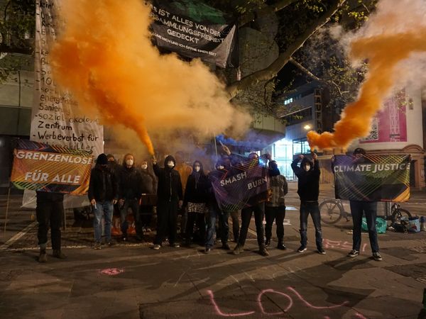 Gruppenbild vom Camp im Dunklen, es werden orange Rauchtöpfe gezündet