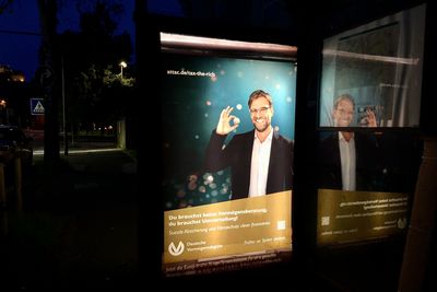 Blick auf eine Bushaltestelle im Dunkeln, bei der das Werbeplakat gegen ein Fake-Plakat ausgetauscht wurde. Auf ihm ist Jürgen Klopp bei einer umgestalteten Werbung der Deutschen Vermögensberatung AG zu sehen und der für die Europäische Bürger*inneninitative "Tax the richt wirbt"