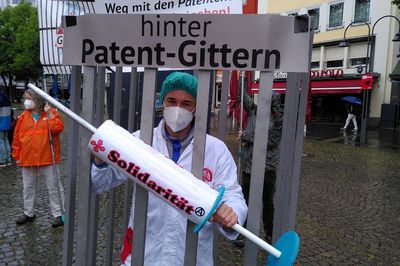 Bild: Jakob Migenda Arzt mit Solidaritätsspritze ist in einem Käfig eingesperrt mit der Überschrift "hinter Patent-Gittern"