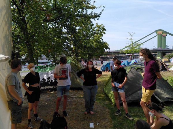 Eine Gruppe von jungen Attacis steht im Klimacamp im Kreis und diskutiert