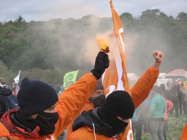 Zwei Attacies mit Mund-Nasen-Maske halten ein Pyro in die Luft und recken die Fäuste