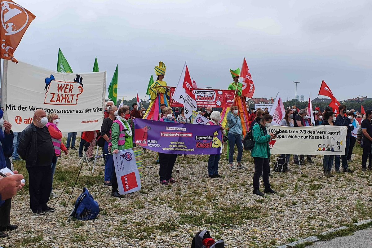 Bild von der Gesamtdemo mit mehreren Transparenten und zahlreichen Fahnen verschiedener Organisationen.