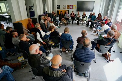 Blick in einen Workshop bei der Menschen in einem Stuhlkreis sitzen