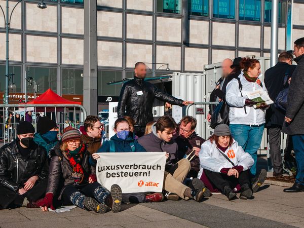 Vor Gittern am Eingang des Energiegipfels sitzen Aktivist*innen und blockieren