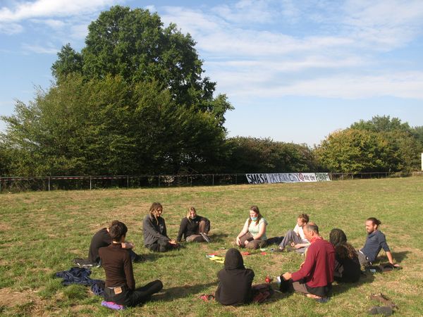 Junge Attacies sitzen im Plenumskreis auf dem Sportplatz von Dannenrod.