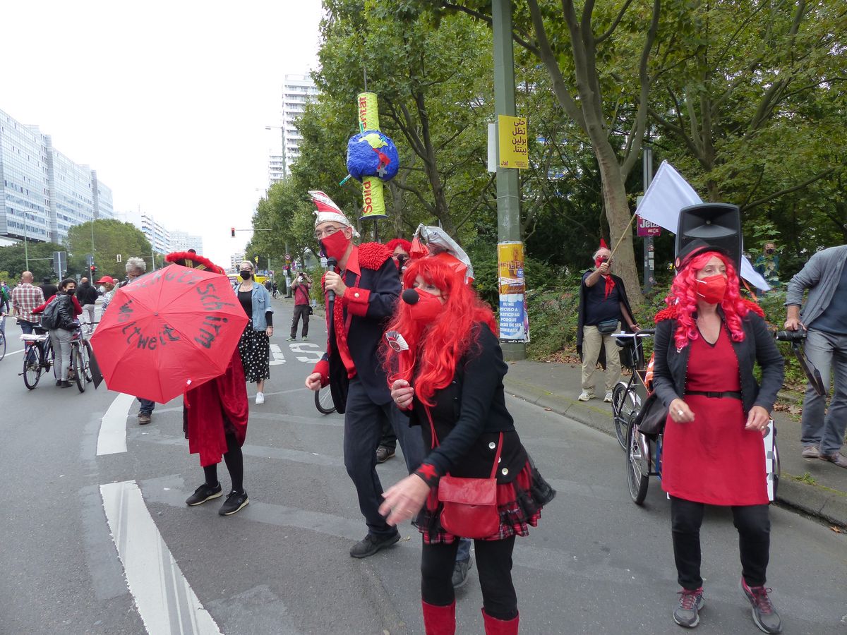Auf dem Bild ist eine Gruppe von Menschen in rot-schwarzen Karnevalskostümen am Rand der Unteilbar-Demo in Berlin