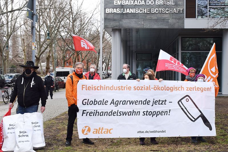 Bild: Uwe Hirsch Bei einer Kundgebung gegen das EU-Mercosur-Abkommen stehen Attacies mit einem Transparent für Agrarwende mit dem Slogan "Fleischindustrie sozialökologisch zerlegen. Globale Agrarwende jetzt – Freihandelswahn stoppen"