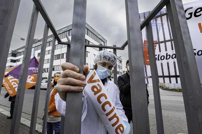 Ein als Arzt verkleideter Aktivist mit einer Übergroßen Impfspritze ist hinter Gittern gefangen.