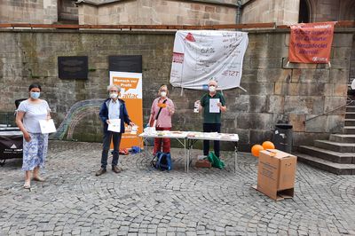 Bild vom Infostand, mit vier Attacies, im Hintergrund ist das Transparent.