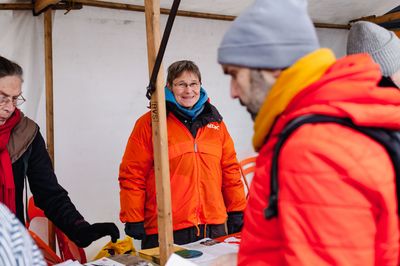 Eine Attac-Aktivistin steht lächelnd am Infostand