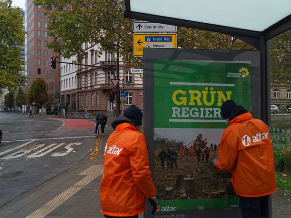 Aktivisten beim Anbringen eines Adbusting-Plakates
