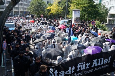 Ein Demoblock mit Menschen in weißen Maleranzügen und dem Fronttransparent "Stadt für alle!" läuft über eine Brücke